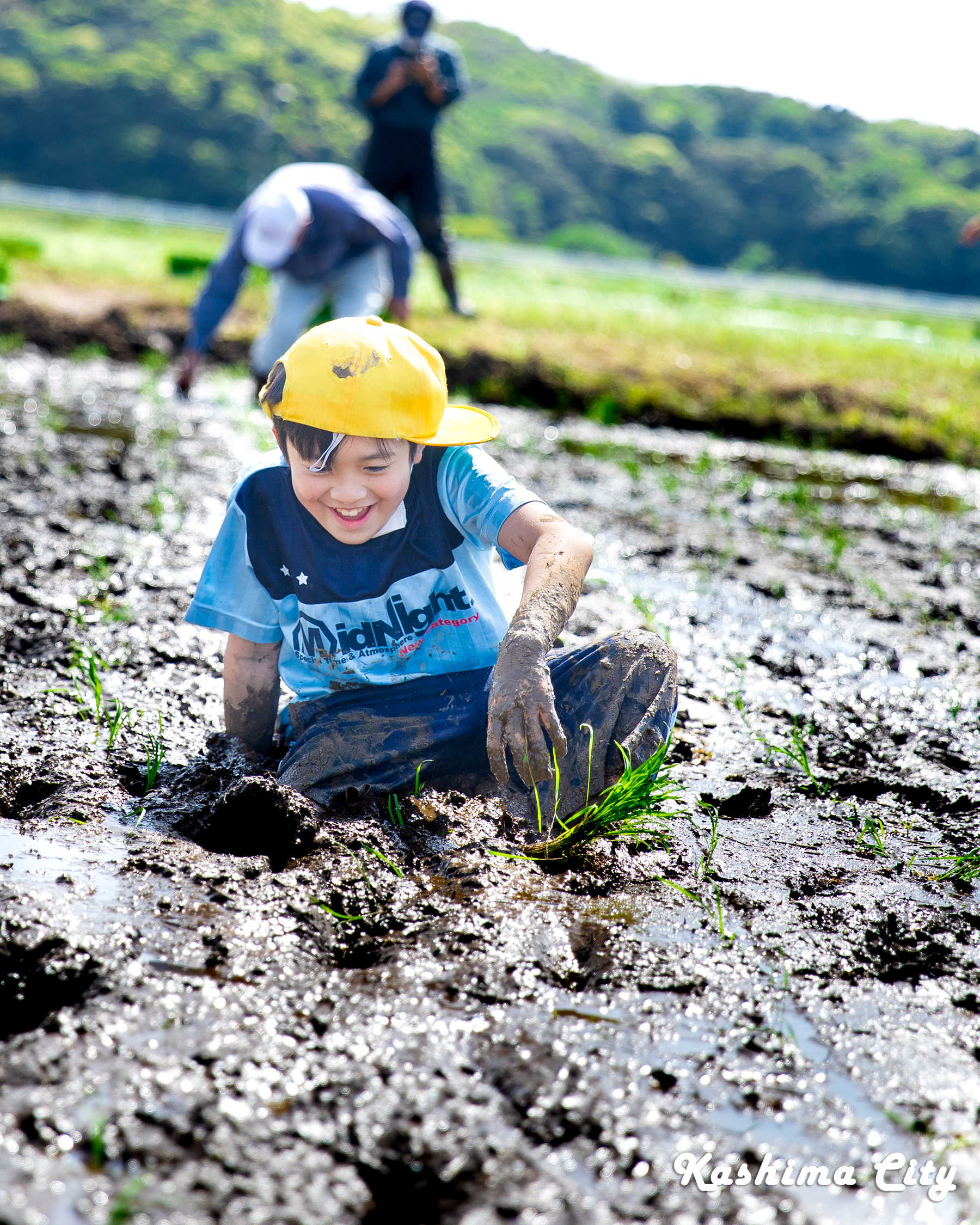 田植え体験でしりもちをつき、泥まみれになる生徒