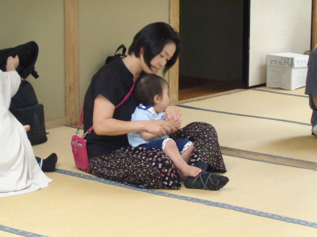 母親の膝の上で手遊びをする幼児