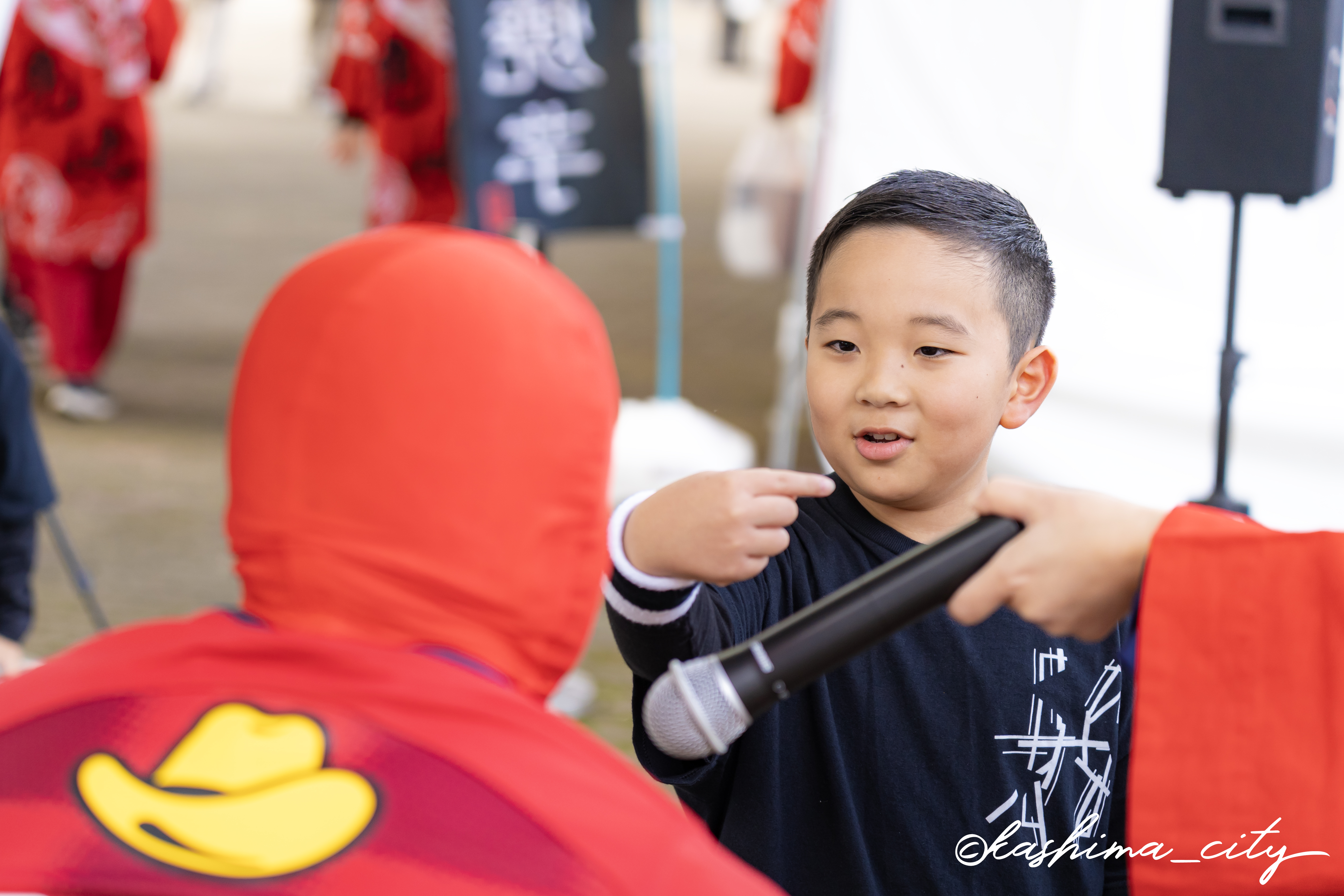 ステージイベントに参加する少年とタイツマン