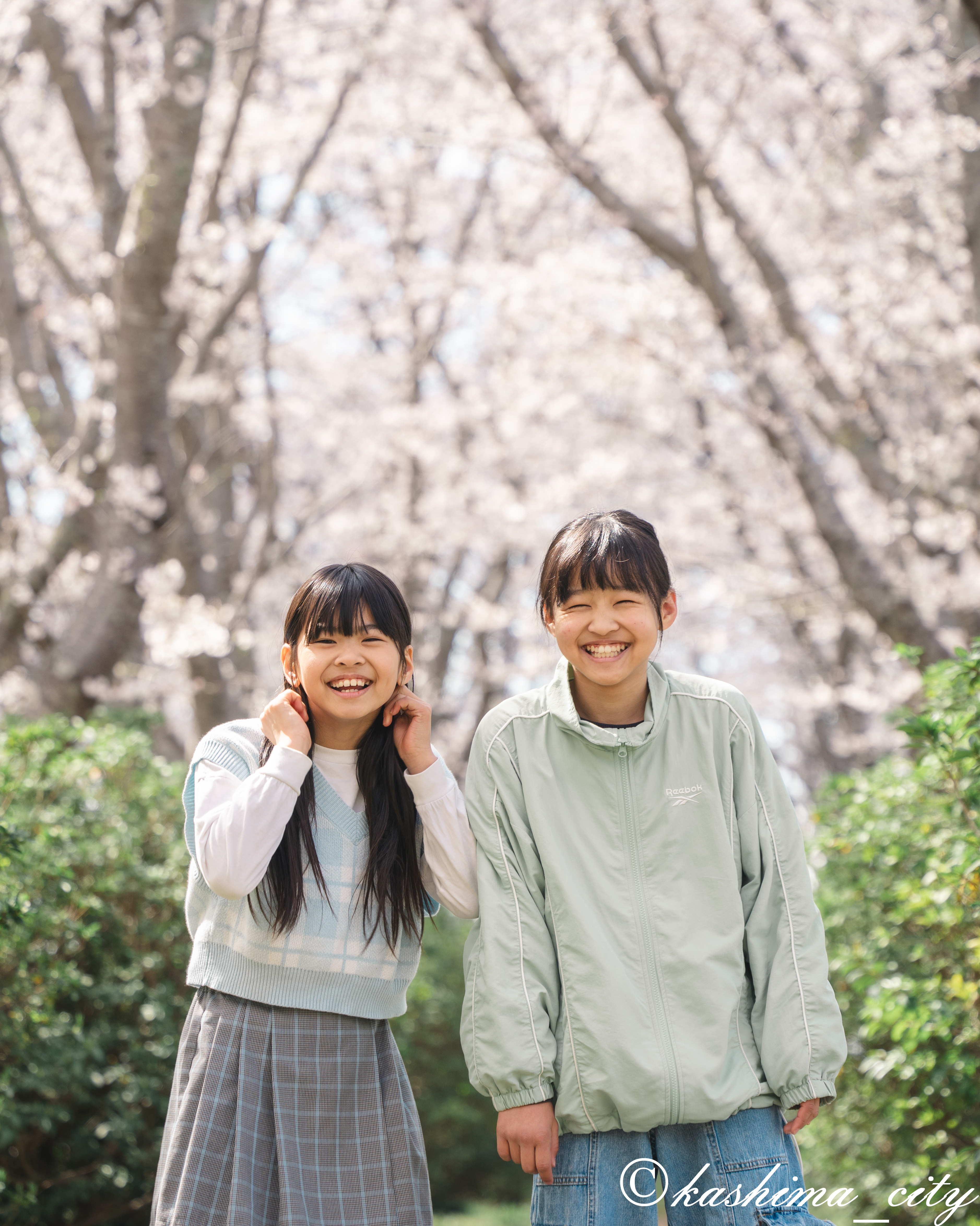 桜の前で笑う女の子２人