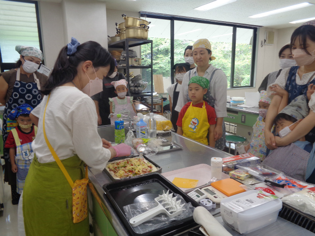 ピザづくりの説明を聞く親子