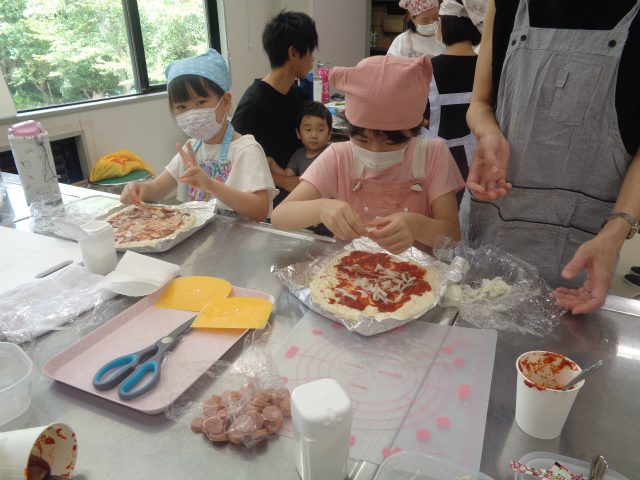 ピザに具材を乗せる子どもたち
