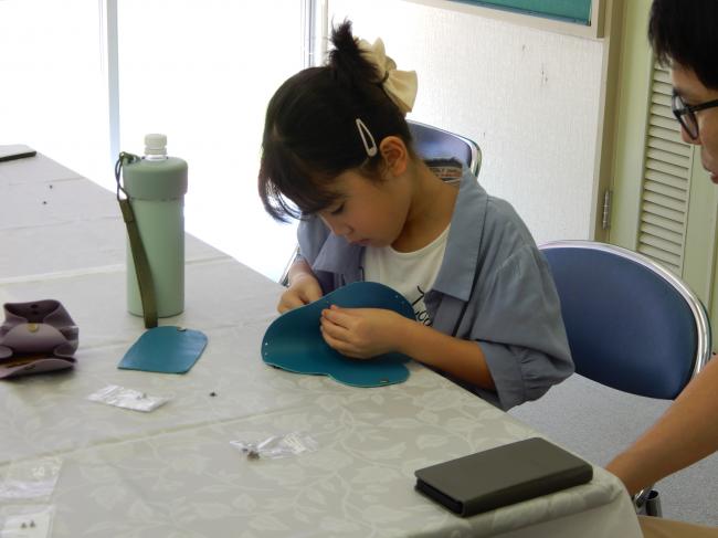 アコーディオンポーチにボタンを仮留めしている児童の様子です。