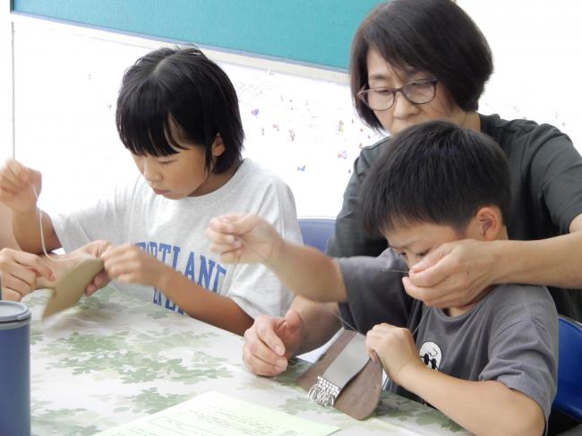 針と糸を使って皮を縫っている子ども達の様子です。