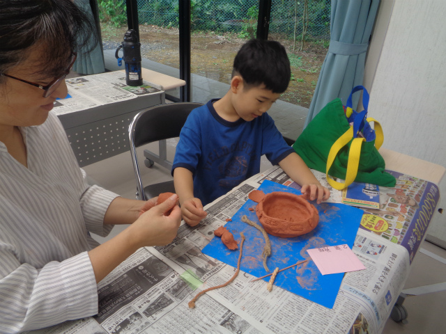 母親と協力して土器を作る子ども