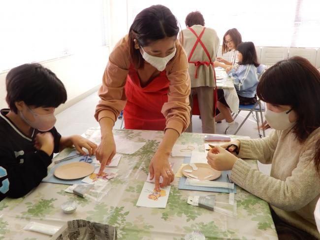 先生にパーツの貼り方を教わっている親子