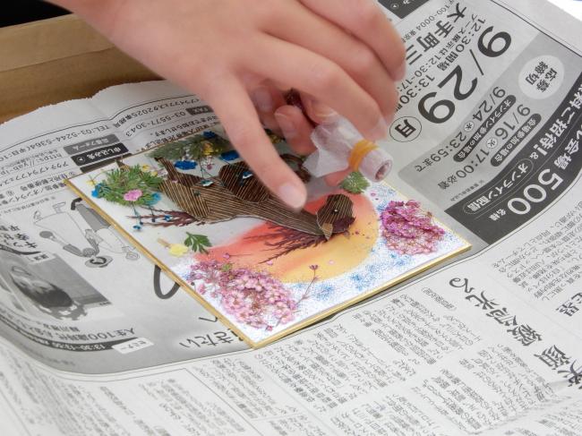 背景になる台紙にラメを振りかける様子