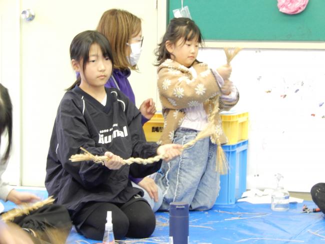 しめ縄を楽しそうに作っている小学生親子