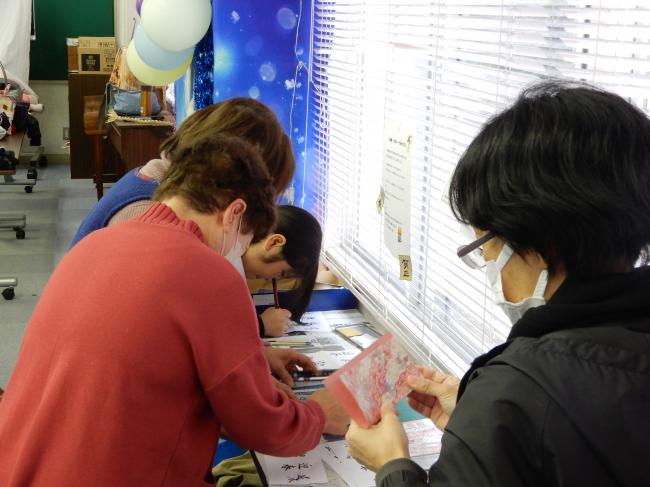 筆ペンを使って迎春の文字を書いている参加者の様子