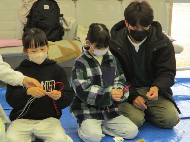 水引をリボンの形に作っている親子の様子