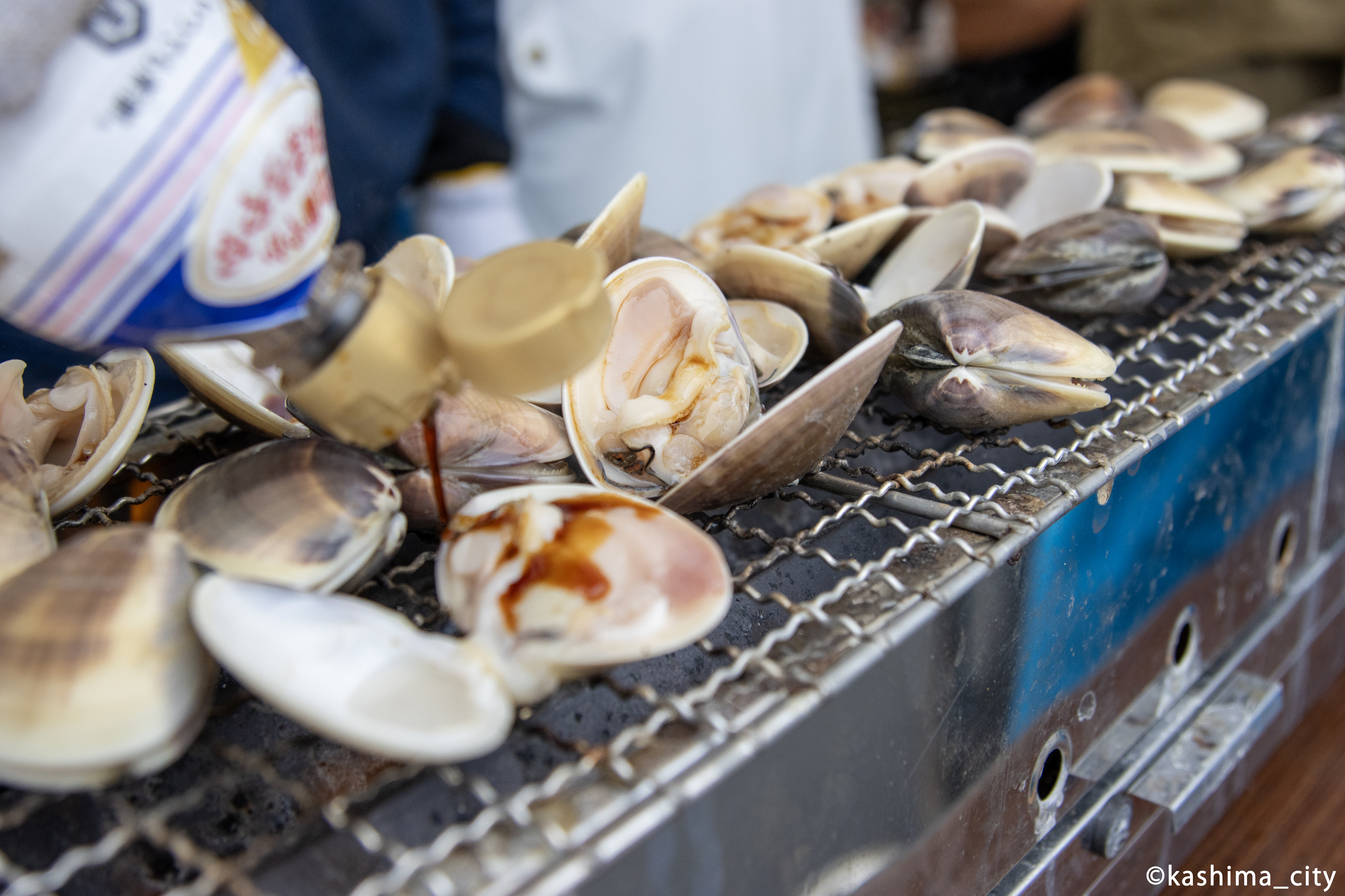 焼いたはまぐりに醤油をかけている