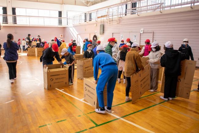 段ボールベッドを設置している児童の写真