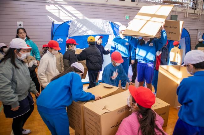 段ボールベッドを設置している児童の写真