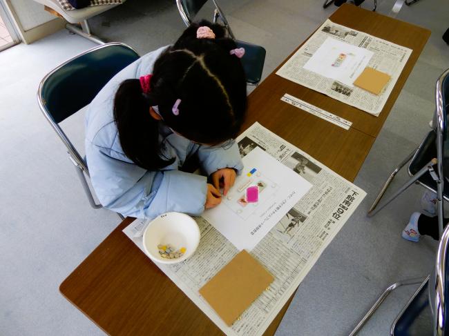 デザインを考えて紙の上にタイルを置いている様子。