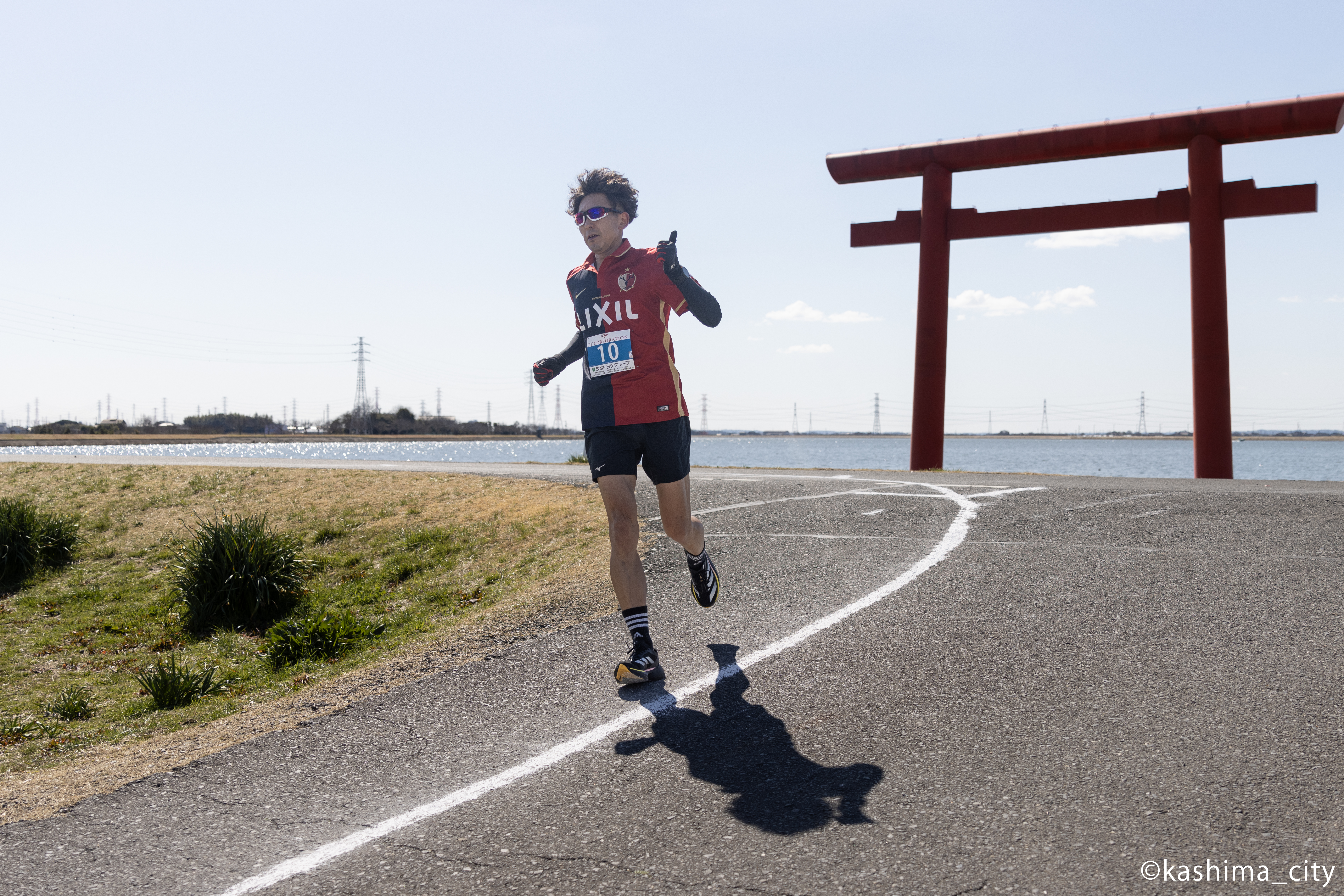 鳥居を背に走る男性