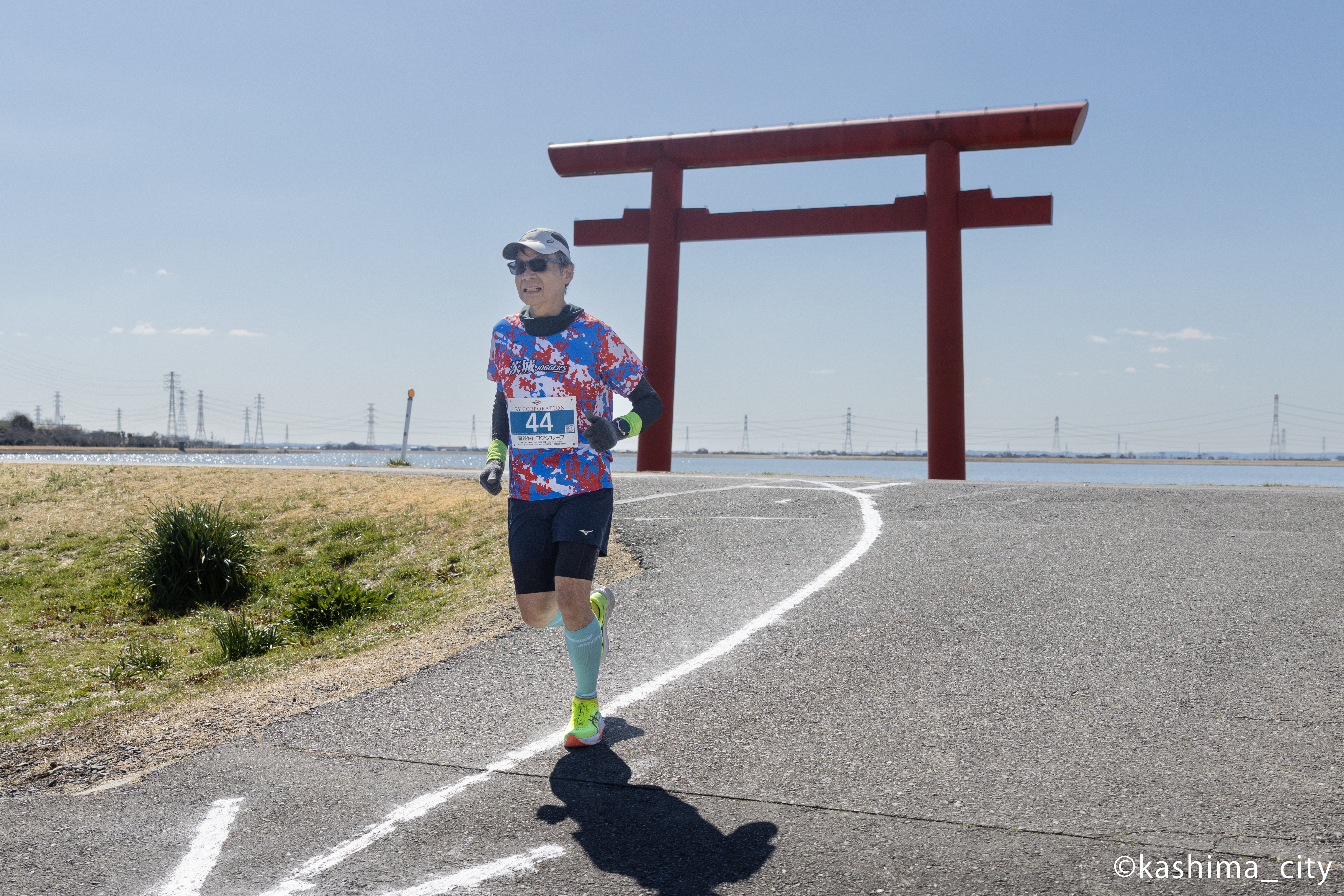 鳥居を背に走る笑顔の男性