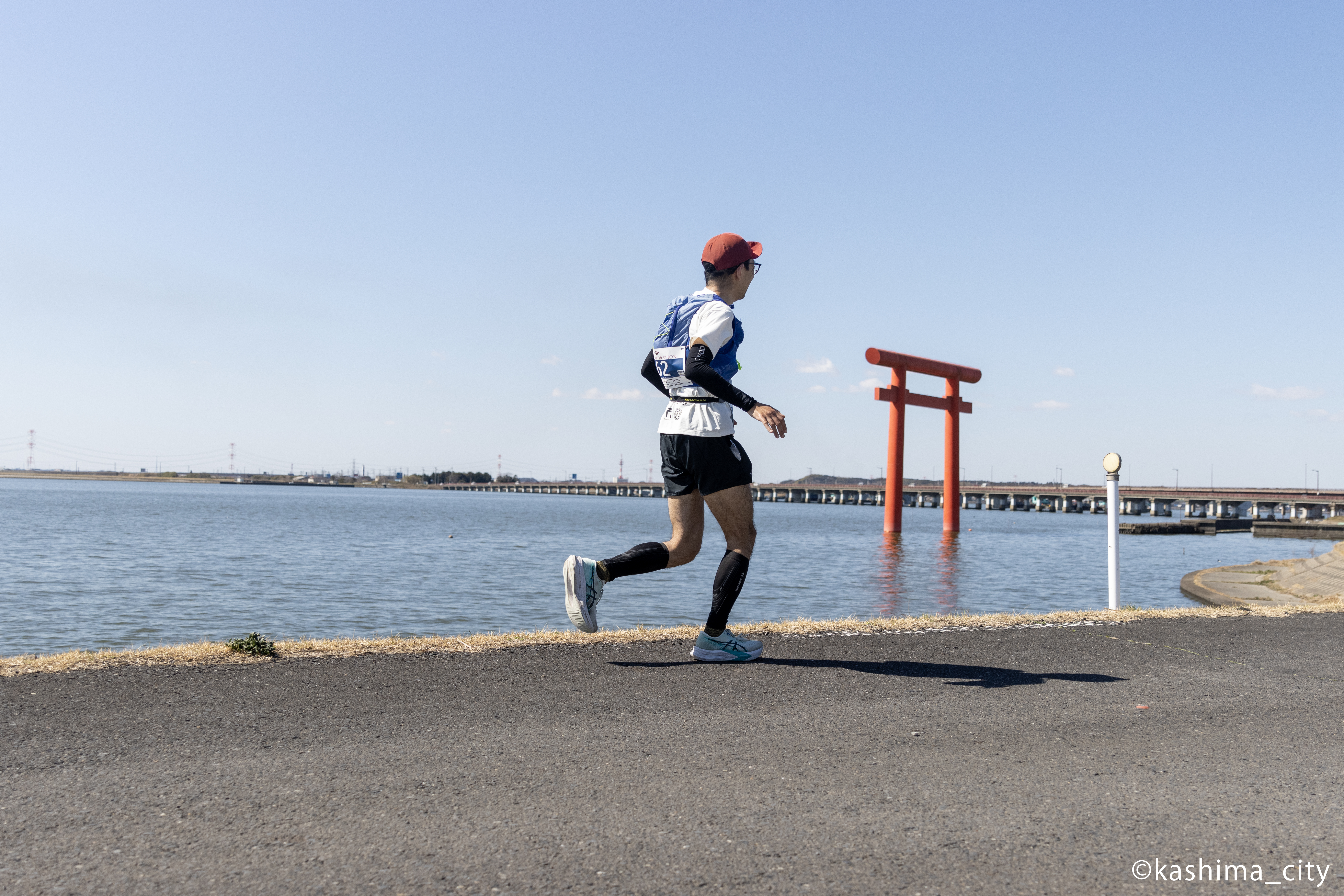 鳥居の横を走る男性の後ろ姿