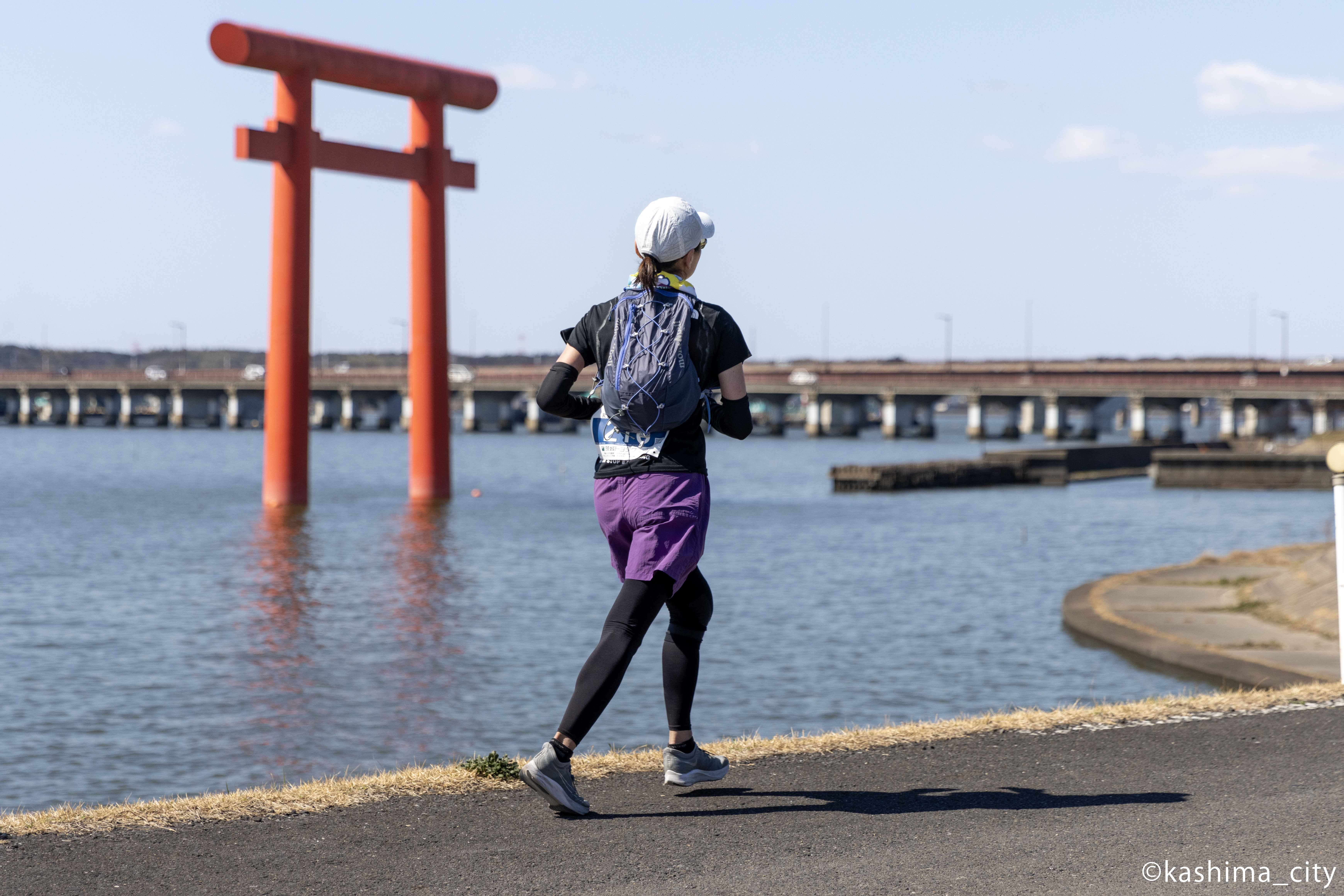 鳥居の横を走る女性の後ろ姿