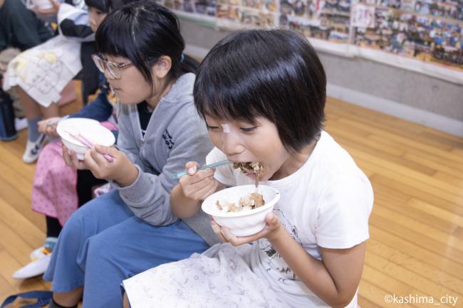 口いっぱいに「かしまし豚のホルモン×豚バラ丼」をほおばる様子