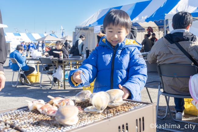 浜焼きバーベキューではまぐりを焼く少年